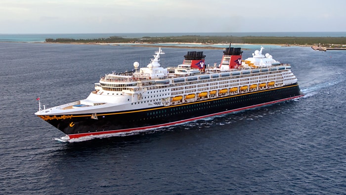 O Disney Magic, um navio com vários decks e uma proa imponente, em alto-mar. 