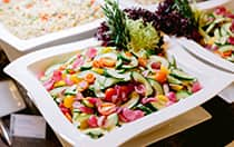 A square plate with a cherry tomato, cucumber and red onion salad from a buffet