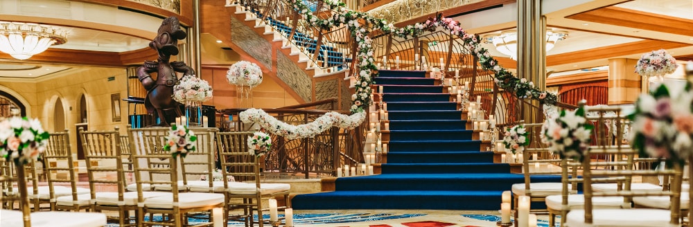 Two groups of chairs face an elegant staircase lined with flowers