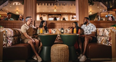Four friends sitting in a booth at the Skipper Society on the Disney Treasure