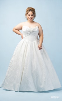 A bride wearing an Aurora inspired ball gown featuring a straight neckline and a bodice with a bow