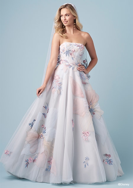 A bride wearing a veil and a strapless Rapunzel inspired A line wedding gown featuring a straight across neckline and large embroidered flowers