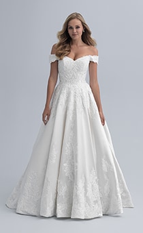 A bride in an off the shoulder wedding dress with a fitted waist and semi full skirt