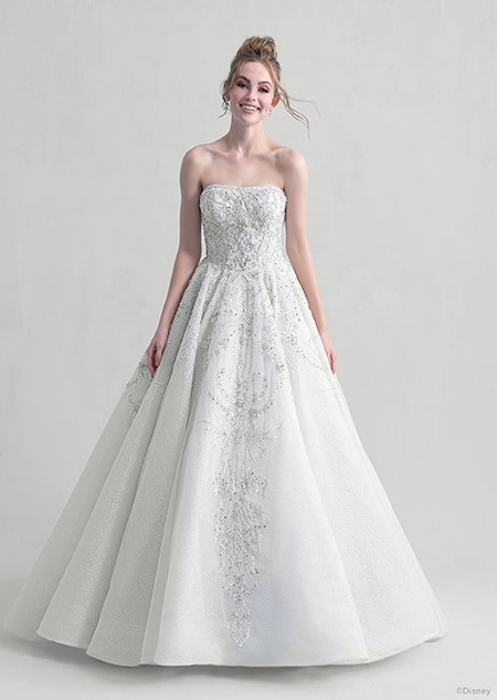 A woman stares down at the Cinderella wedding gown from the 2021 Disney Fairy Tale Weddings Platinum Collection that she is wearing