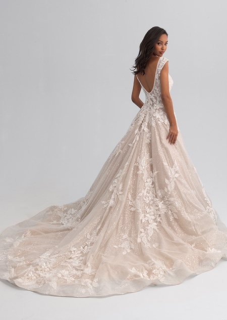 A woman looking over her shoulder wearing a sleeveless wedding gown covered with a shimmery lace A woman looking over her shoulder wearing a sleeveless wedding gown covered with a shimmery lace