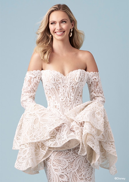 A bride wearing a strapless Jasmine inspired mermaid wedding gown featuring lace, a sweetheart neckline and ruffled off the shoulder sleeves