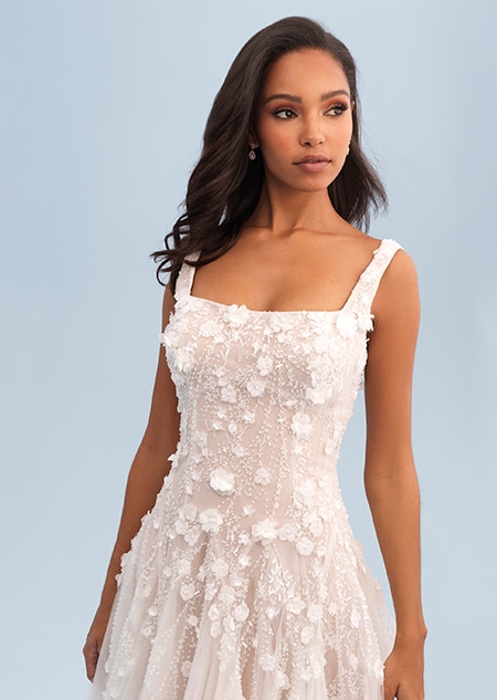 A woman wearing a wedding dress with ornate beadwork along the bodice and skirt A woman wearing a wedding dress with ornate beadwork along the bodice and skirt