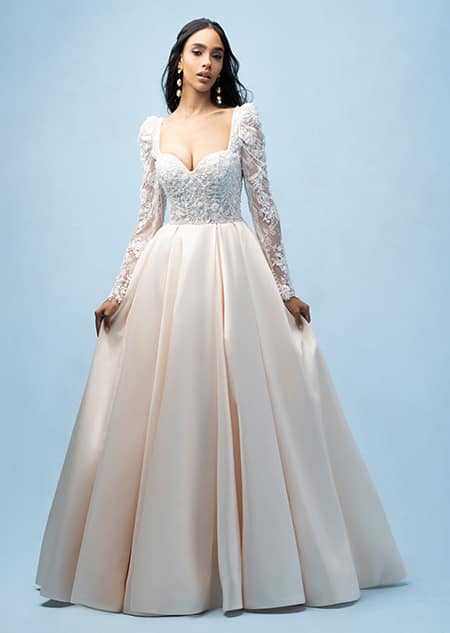 The front of a bride wearing a Belle inspired ball gown featuring a sleeved, beaded bodice with a sweetheart neckline