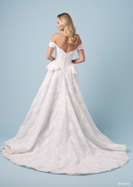 The back of a bride wearing a Cinderella inspired A line gown featuring off the shoulder sleeves and short panniers on the hips