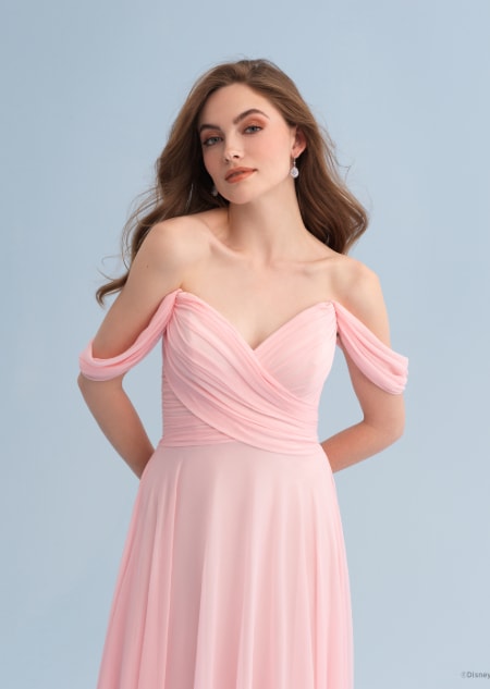 A woman wearing an Aurora themed bridesmaid dress with a V neckline and off the shoulder sleeves