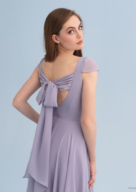 A woman wearing a Rapunzel themed bridesmaid dress with a bow across the back