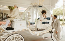 A bride stepping down from Cinderella’s horse drawn carriage into the arms of her groom