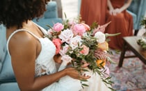 A bride holding a bouquet of flowers while sitting on a sofa