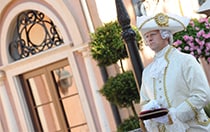 A performer dressed in 15th century attire awaits holding a plush velvet pillow