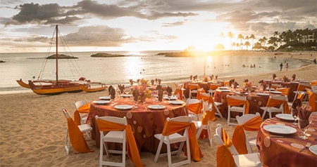 Set tables on a beach during sunset at Aulani Beach