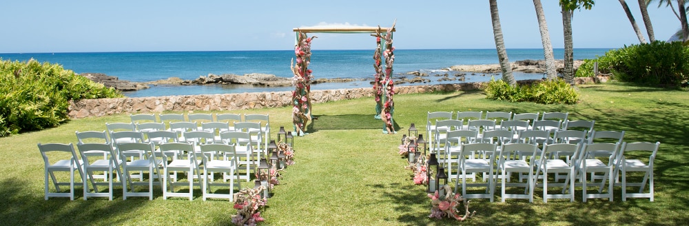 Folding chairs on both sides of an aisle leading towards an altar on a lawn by the ocean
