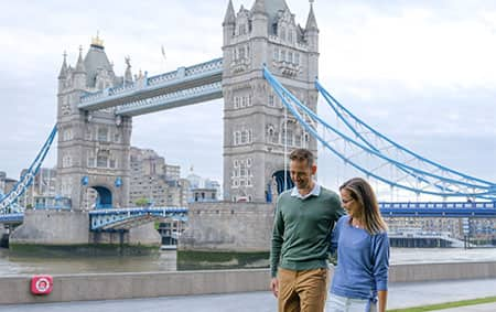 Newlyweds strolling along the River Thames in front of the Tower Bridge in London, England