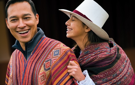 A man and a woman wearing traditional outfits share a laugh