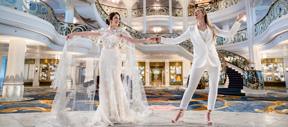 Two brides dancing on the stage of the Grand Hall on the Disney Wish