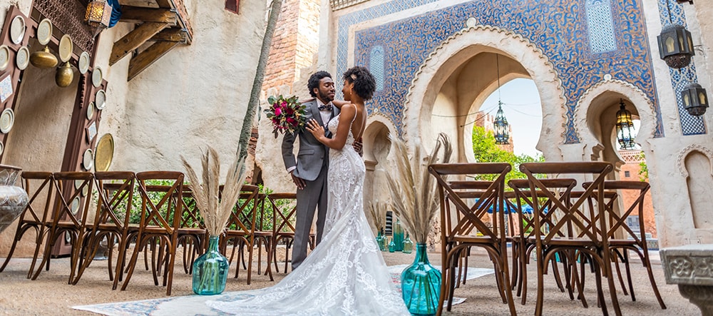 A bride and groom stand amid empty chairs and gaze into each other’s eyes in the EPCOT Morocco Pavilion at Walt Disney World Resort