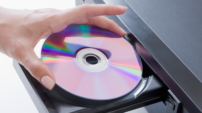 A woman's hand puts a DVD into a DVD player