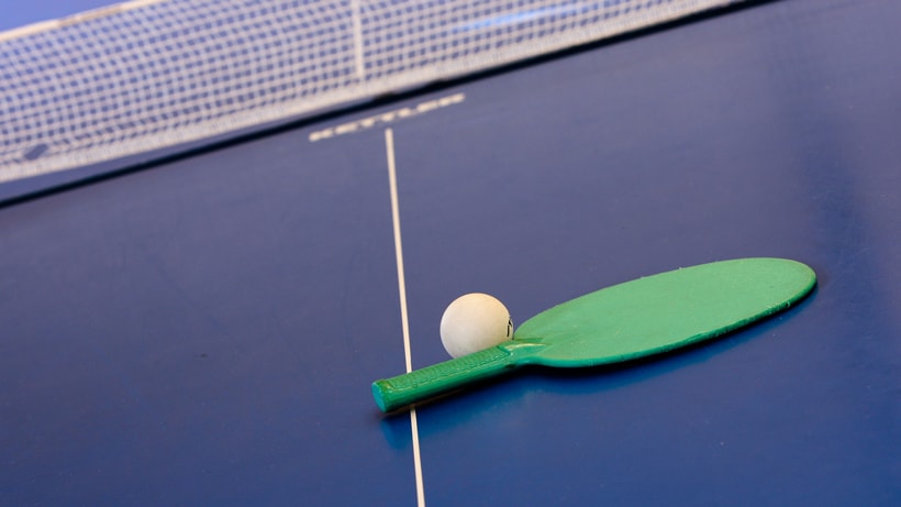 A ping pong ball and paddle on a ping pong table