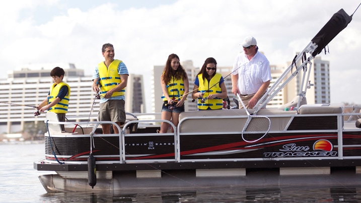 A fisherman and a family fishing from a pontoon boat on a lake