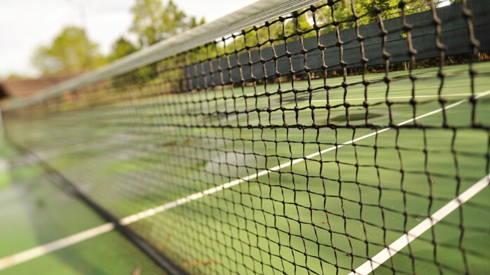 A tennis court as seen through the web of a tennis net