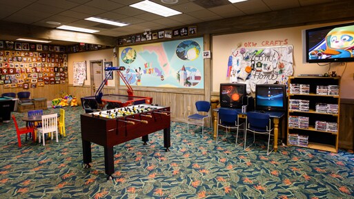 テーブルサッカー、2 台のコンピューター、子供サイズのテーブルと椅子、子供のアート作品があるコミュニティー・センター
