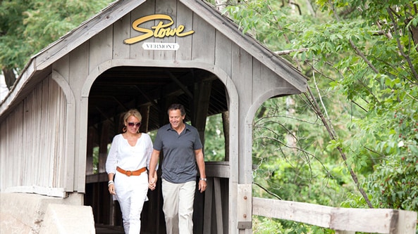 A couple walking along a wooden bridge in Stowe Vermont