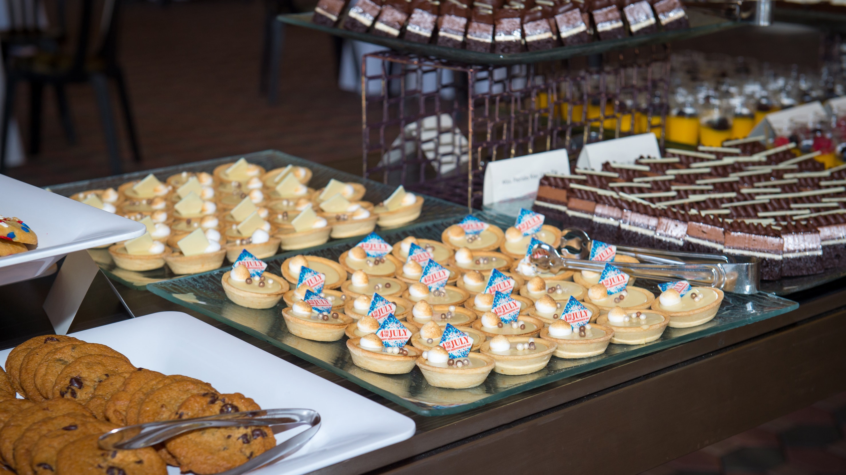 Several trays filled with bite sized desserts like chocolate chip cookies, brownies and more