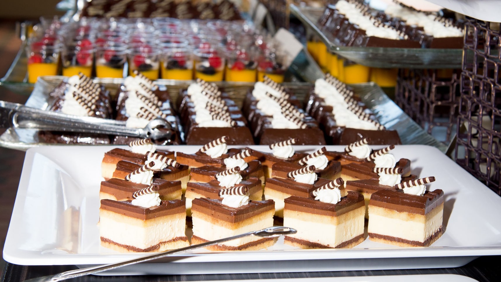 Large plates with desserts including tiramisu topped with a dollop of whipped cream