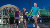 A family of 4 walking by Space Mountain at night