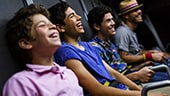 4 teenage boys sitting down and laughing