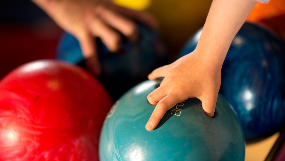 A bowling ball being lifted by a child's hand