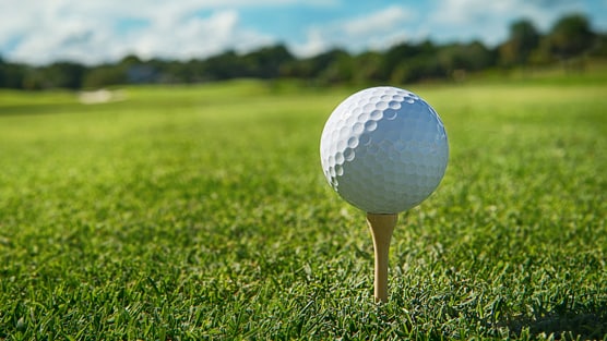 A golf ball on a tee amid a serene golf course