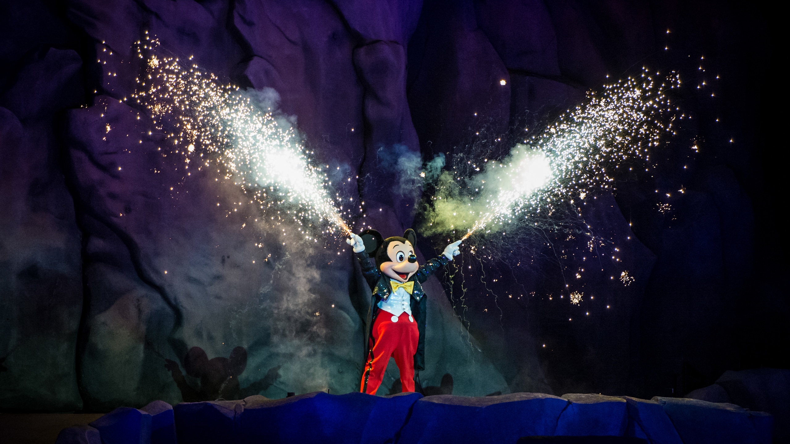 Mickey smiles while holding sparklers above his head
