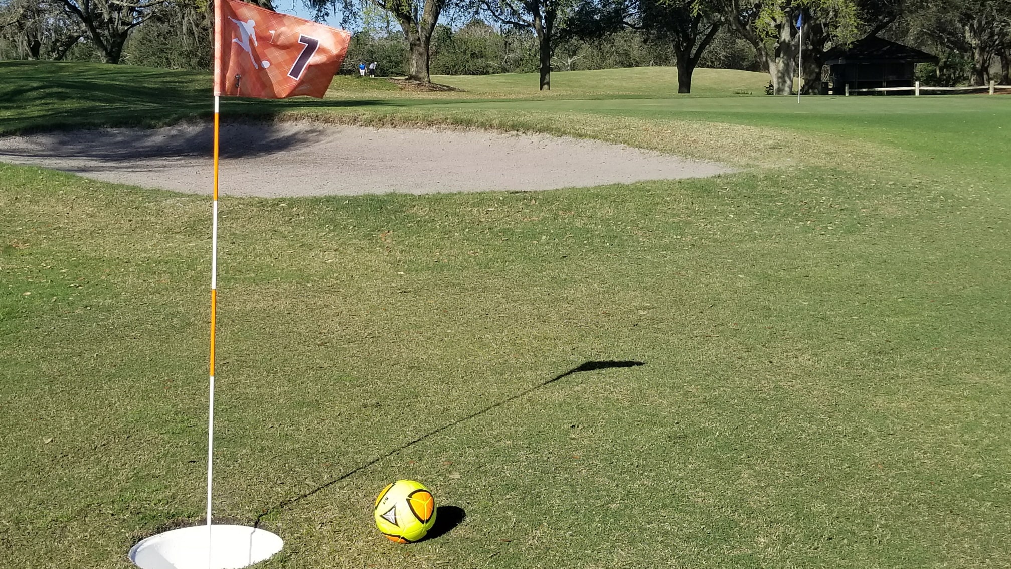 A soccer ball near a sand hazard on a FootGolf course