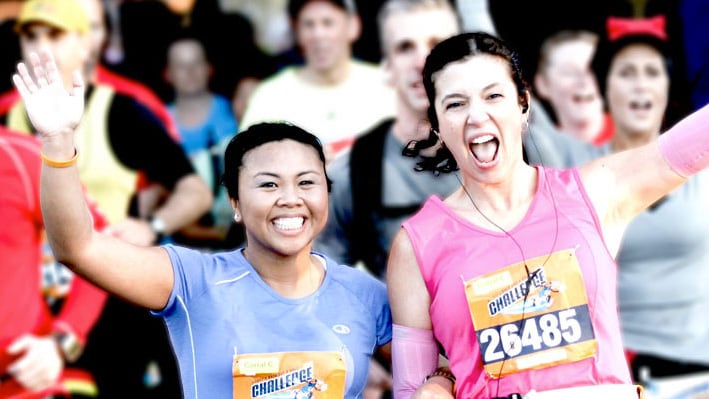 Two female runners smiling and waving