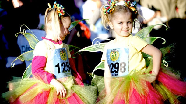 Two small girls wearing race bibs and fairy costumes