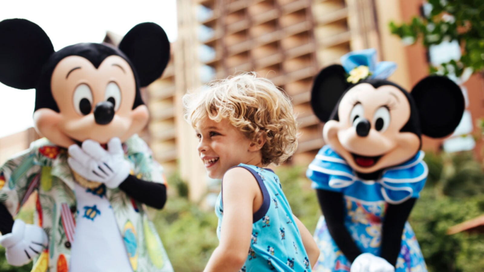 A toddler smiles after seeing tropically dressed Mickey and Minnie Mouse