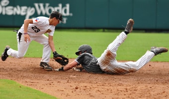 A baseball player slides into a base while his opponent reaches to tag him out
