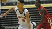 AAU Boy's Basketball A teenage male basketball player dribbles past an opponent