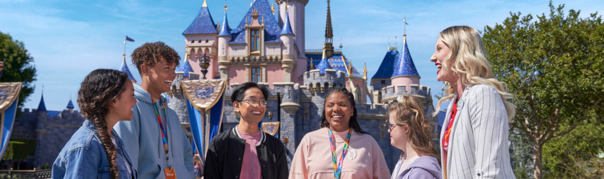 A Cast Member and 5 students stand in front of Sleeping Beauty Castle in Disneyland Park