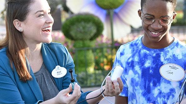 A Cast Member holding wires and equipment talks to Disney Imagination Campus students