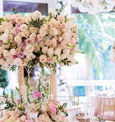 Some set tables with large floral centerpieces and glass goblets with water